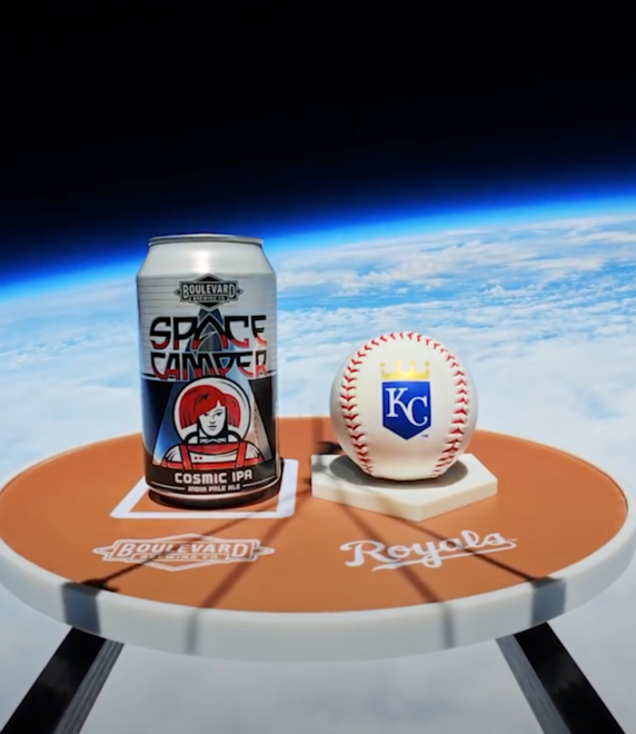 A can of Space Camper Cosmic IPA and a Kansas City Royals baseball sit on a small round table with "Boulevard" and "Royals" logos, floating high above Earth with the curvature and atmosphere visible in the background.
